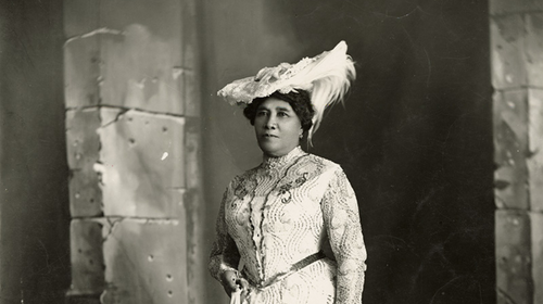 Black and white bust portrait of Queen Liliuokalani of the Kingdom of Hawaii c.1900 in a feather hat and light color dress.