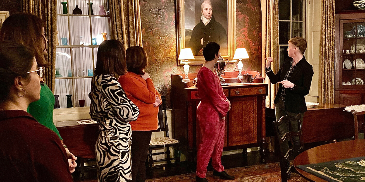 Visitors and guide viewing a painting in the dining room.